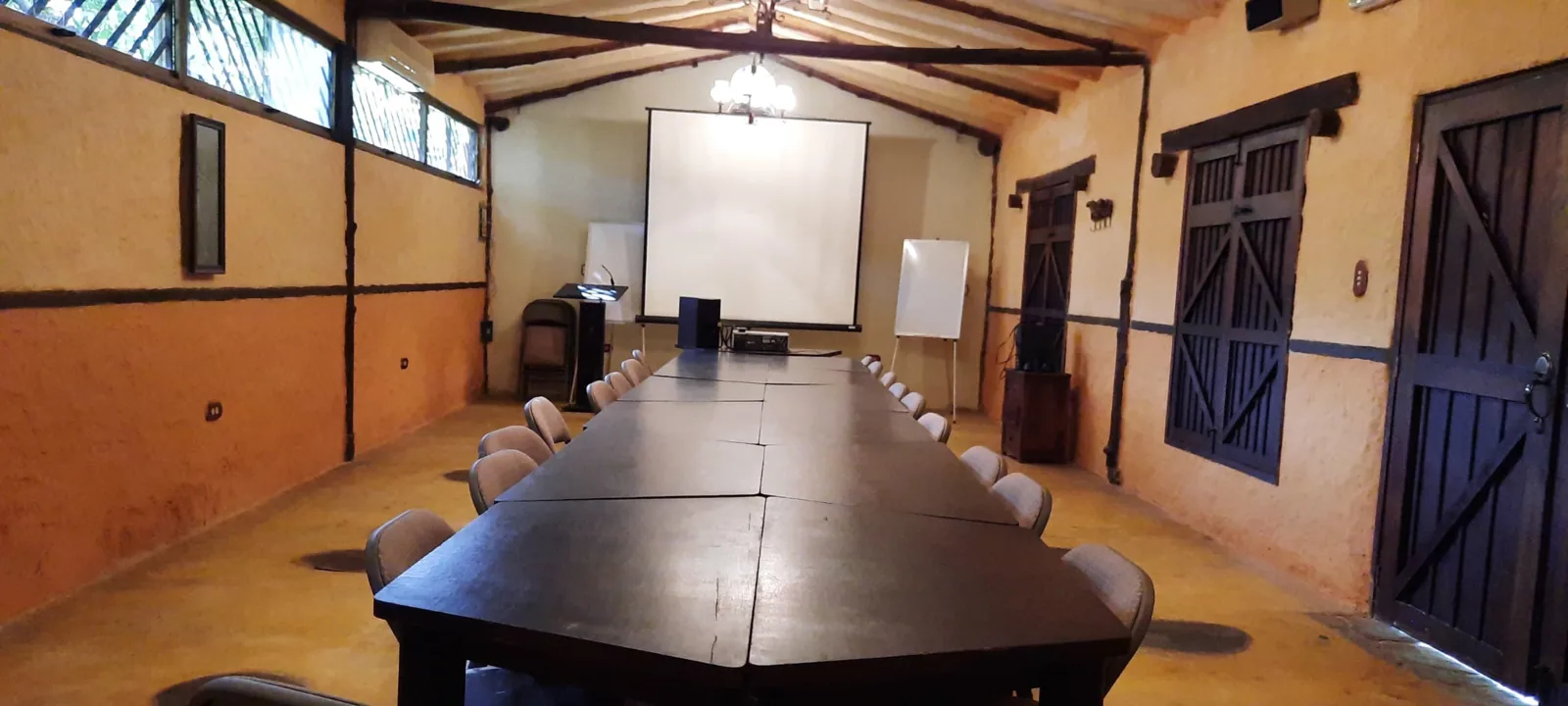 Salón de conferencias con mesas, sillas y pantalla de proyección